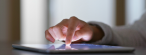A hand navigating a touch screen device on a table